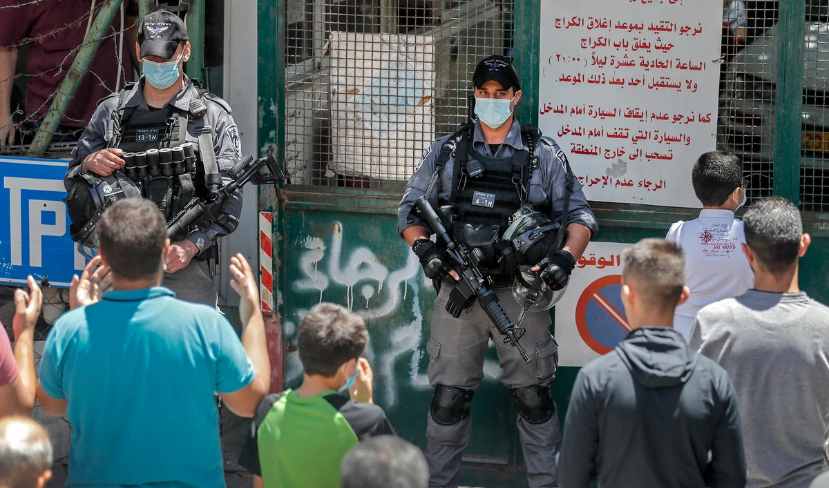 Israeli security forces wearing protective face masks stand before Palestinian worshippers gathering to attend Friday prayer outside the closed al-Aqsa mosque compound in Jerusalem's Old City, amid measures to stem the spread of the coronavirus Covid-19, on May 29, 2020. (AFP)