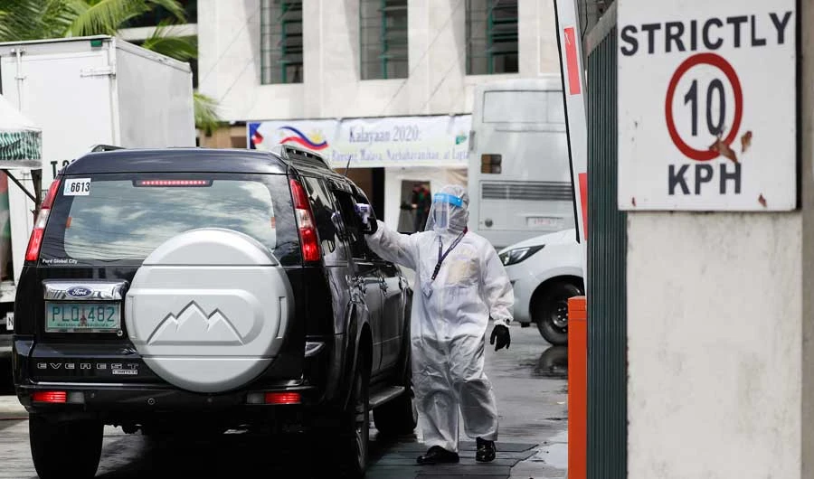 A security guard wearing a protective suit to help prevent the spread of the new coronavirus checks the temperature of a visitor entering the Department of Agriculture compound in Metro Manila, Philippines, Wednesday, June 10, 2020. (AP)