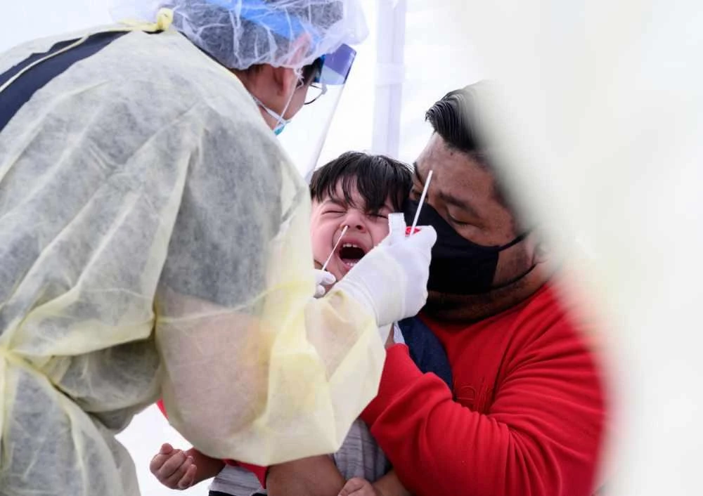 A nurse takes a nasal swab sample to test for COVID-19 at a mobile testing station in a public school parking area in Compton, California. (AFP File Photo)