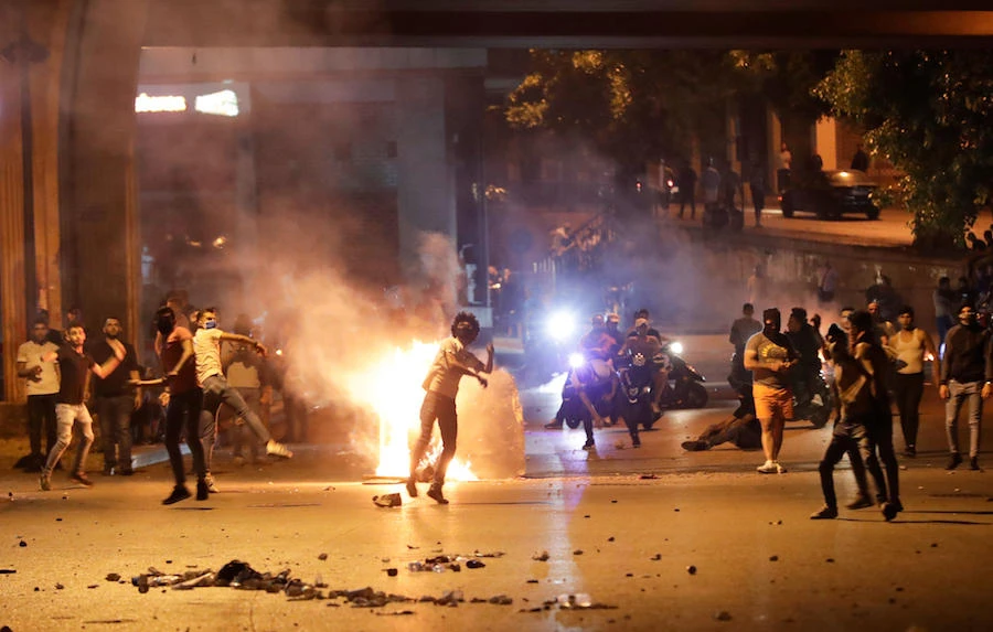 Anti-government protesters hurl rocks at Lebanese security forces, under the Fuad Shehab bridge known as the Ring, during a demonstration against dire economic conditions, in the capital Beirut, late on June 12, 2020. (AFP)