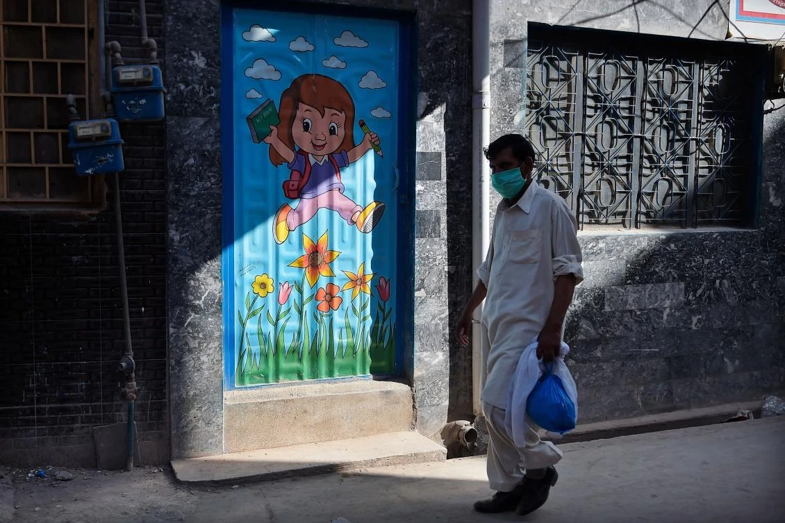 A man wearing a facemask walks past a school on the outskirts of Islamabad on June 14, 2020. Pakistan on June 14 predicted that the number of coronavirus cases could more than double by the end of the month, as the country pledged to ramp up testing. (AFP)