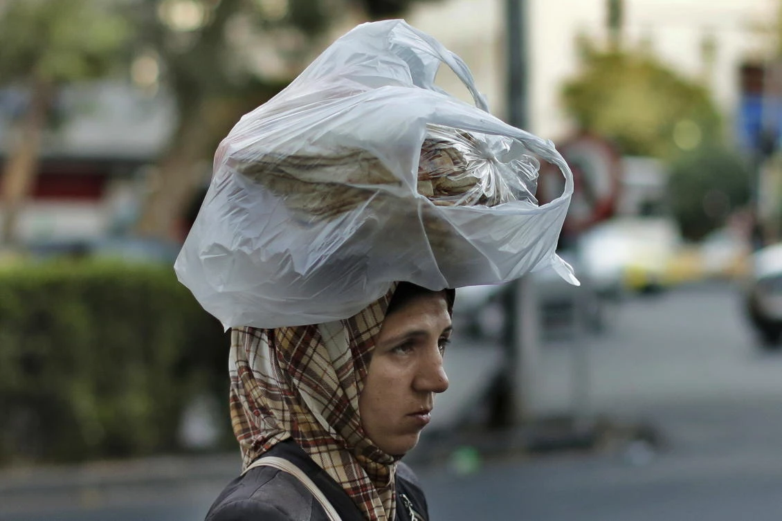 In this July 24, 2019 file photo, a woman carries bread on her head while she crosses a street in the Syrian capital, Damascus. In Syria nowadays, there is an impending fear that all doors are closing. (AP)