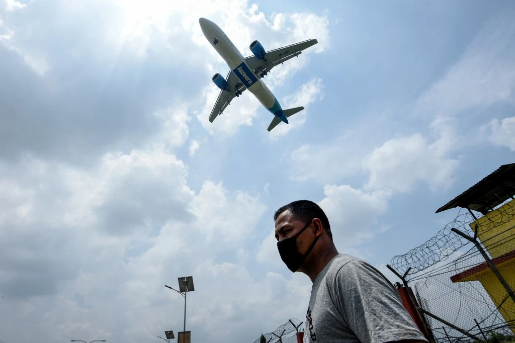 A Jazeera Airways plane approaches to land while a man wearing a facemask as a preventive measure against the spread of the COVID-19 coronavirus walks under at the Tribhuvan International airport in Kathmandu on June 11, 2020. (File/AFP)
