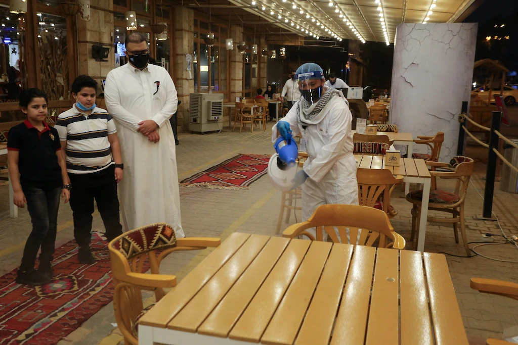 A worker wears a protective suit, following the outbreak of the coronavirus disease (COVID-19), sterilizes the tables before the customers sit down after a restaurant reopened, in Riyadh, Saudi Arabia June 13, 2020. Picture taken June 13, 2020. (Reuters)