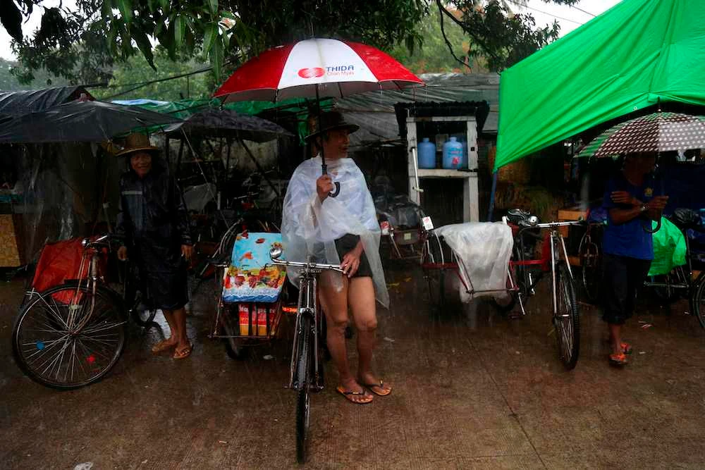 Trishaw drivers wait for customers during heavy rainfall in Yangon, Myanmar, June 14, 2020. (AFP)