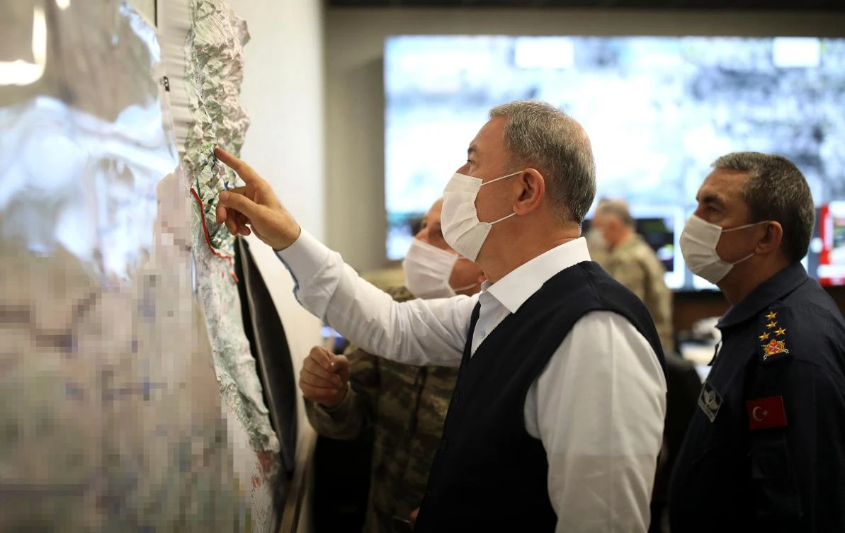 A handout image made available by the Turkish Ministry of Defense Press Office on June 17, 2020, shows the Turkish Minister of Defense Hulusi Akar looking at a map with members of the Turkish Armed Forces Command during a meeting at the Army Command Control Center in Ankara during the military operation dubbed "Claw-Tiger" on June 17, 2020. (AFP)