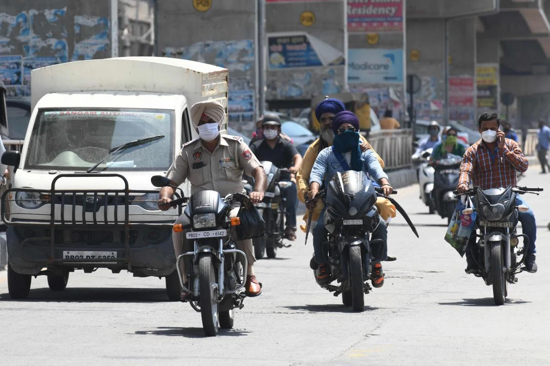 Commuters wearing face masks move through a road in Amritsar on June 17, 2020. (AFP)