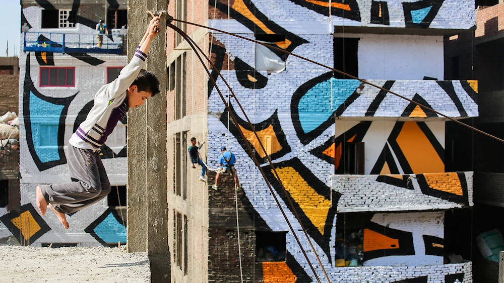 El-Seed working with Zareeb Community in Egypt on his iconic Mural 'Perception' (Photo: Courtesy of El-Seed-art.com)
