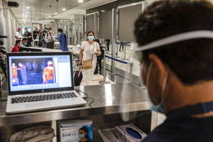 A health worker at Cyprus’ Larnaca International Airport views a laptop screen showing a feed from an infrared camera to monitor the ambient body temperatures of incoming travelers upon their arrival as part of screening for symptoms of COVID-19 coronavirus disease. (File/AFP)