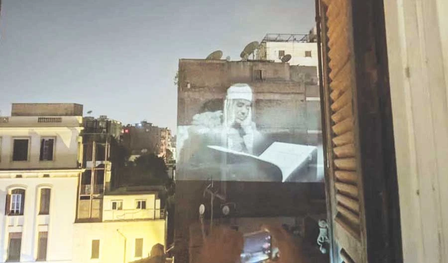 An artist uses a projector to present Qur’anic recitations by an Islamic scholar on a building wall in the El-Mounira area in Cairo. (Photo/Supplied)