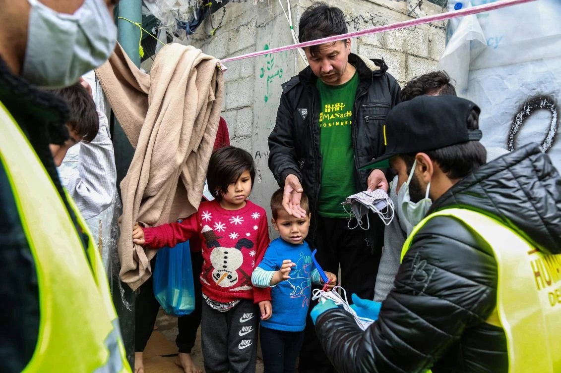 Members of an NGO share handmade protective face masks to migrants and refugees in Lesbos on March 28, 2020. (AFP)