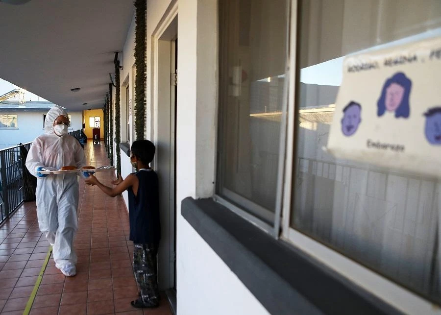Cuban doctor Janeth Blanco delivers food to a Brazilian migrant boy at the so-called 'filter hotel', rented by the World Organization for Peace (WOFP) and the United Nations International Organization for Migration (IOM-UN). (File/AFP)