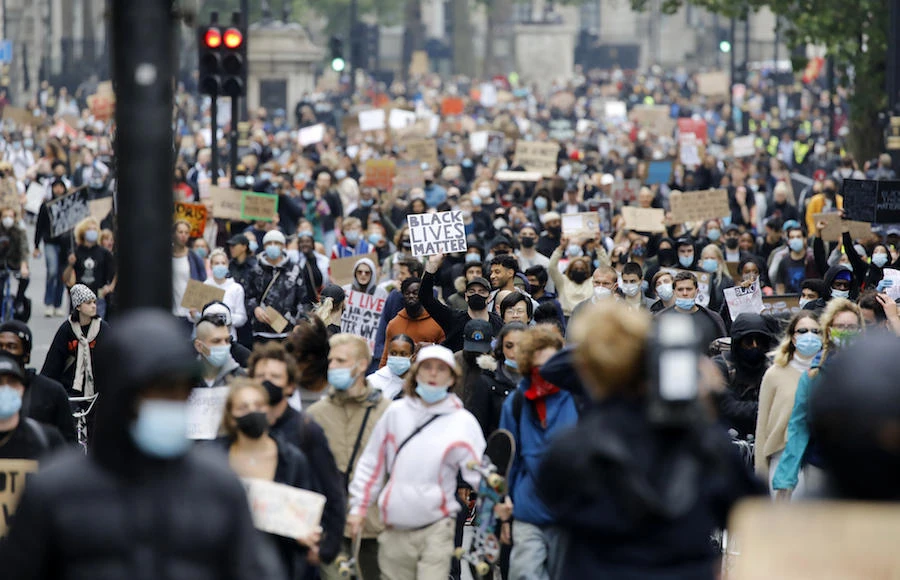 Activists, some wearing face coverings or face masks as a precautionary measure against COVID-19, hold placards as they attend a Black Lives Matter protest march to Trafalgar Square in London on June 12, 2020. (File/AFP)