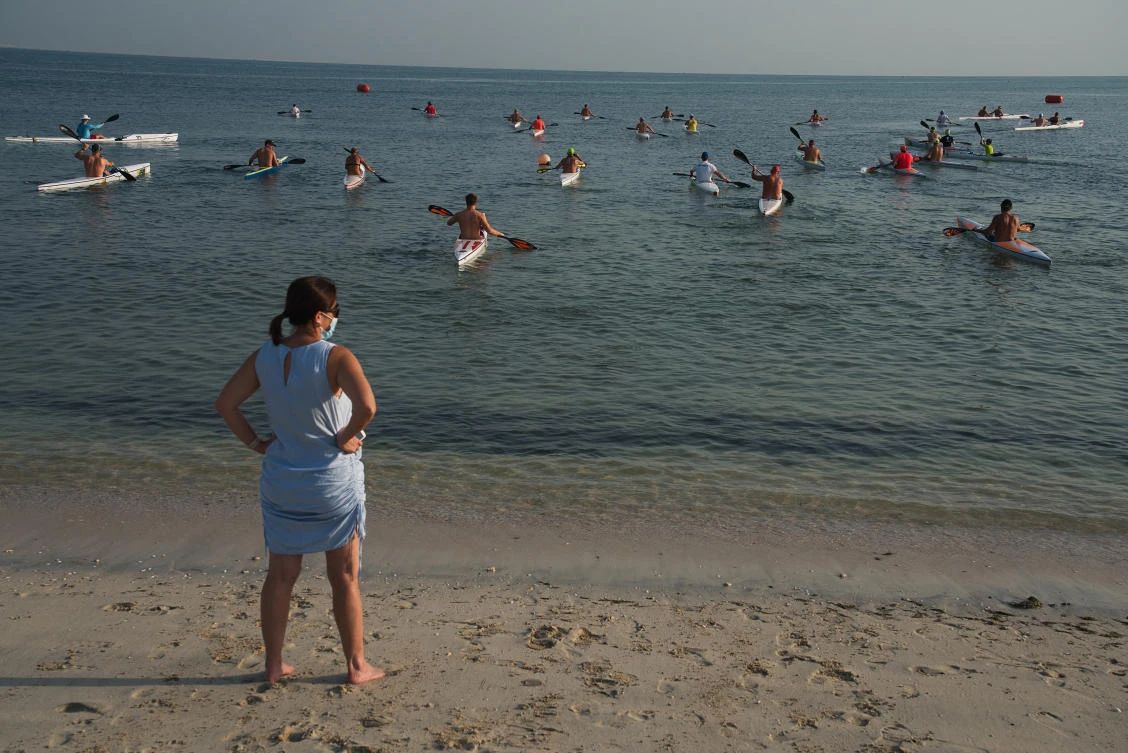 A woman wearing a face mask due to the coronavirus pandemic watches kayak racers take off from the coast of Dubai, United Arab Emirates, Friday, June 19, 2020. (AP)