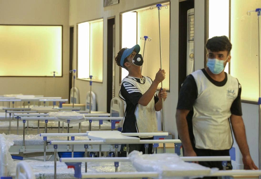 Iraqi volunteers with the Aqiq Institution for Charity work on building a 525-bed field hospital at the Baghdad International Fair exhibition center in the capital Baghdad, on June 21, 2020, a facility the association is setting up as part of the efforts to curb the spread of the COVID-19 pandemic. (AFP)