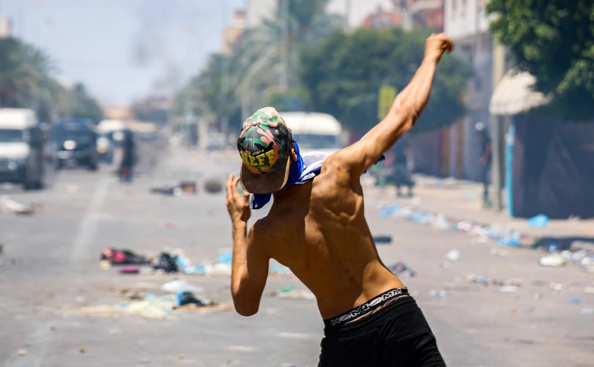 A protester from Tunisia's Tataouine region throws stones during clashes with security forces, firing tear gas, amidst a demonstration in the southern city on June 21, 2020. (AFP)