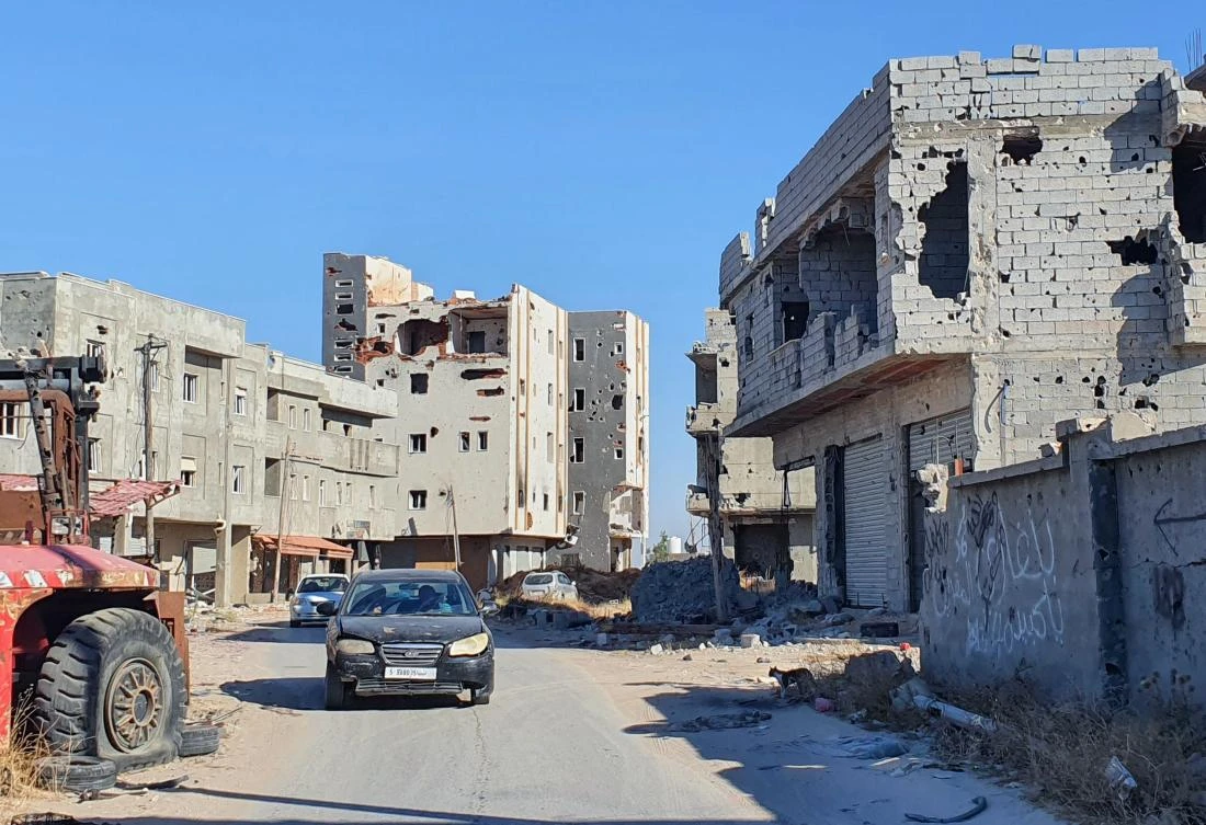 Cars advance on an empty road lined with damaged buidlings in the Salaheddin district south of the Libyan capital Tripoli, on June 21, 2020, as some residents return to the area after it has been demined. (AFP)