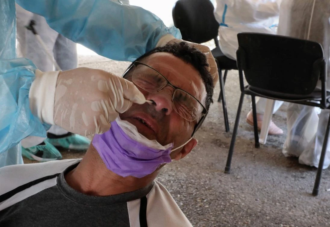 A doctor affiliated with the Palestinian Health Ministry collects samples to test for the novel coronavirus in a mobile tent in the West Bank city of Hebron, on June 22, 2020, two days after the Palestinian Authority temporarily closed the city in a bid to contain the spread of the COVID-19 pandemic amid a sharp rise in infections. (AFP)