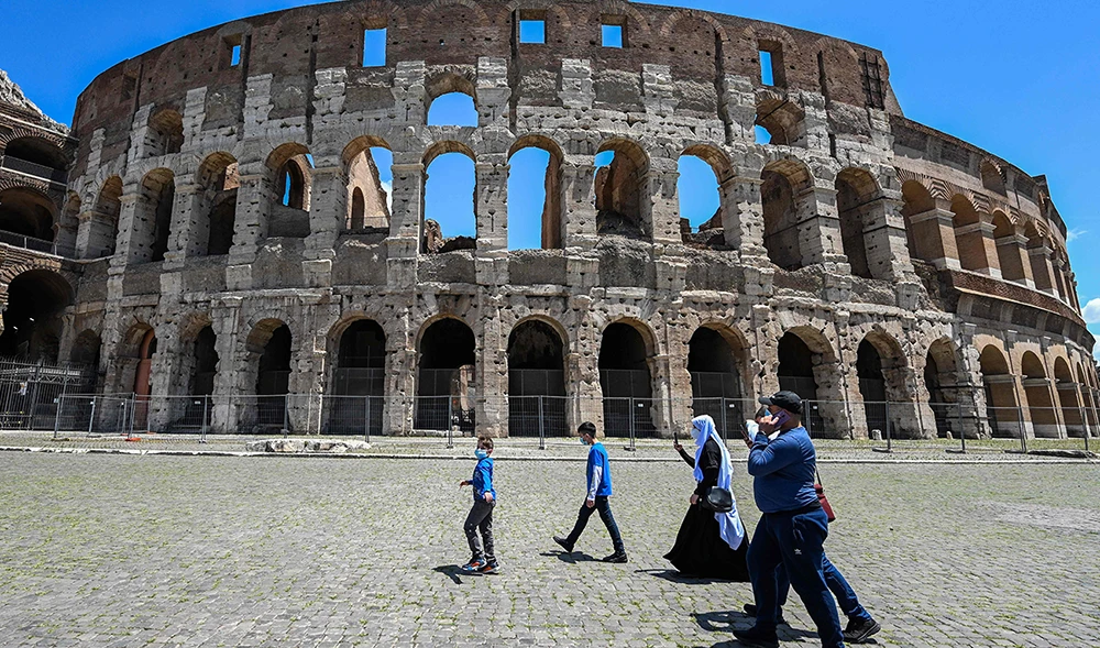 Tourists walk on June 22, 2020 by the Coliseum monument in Rome, as the country eases its lockdown aimed at curbing the spread of the COVID-19 infection, caused by the novel coronavirus. (AFP)