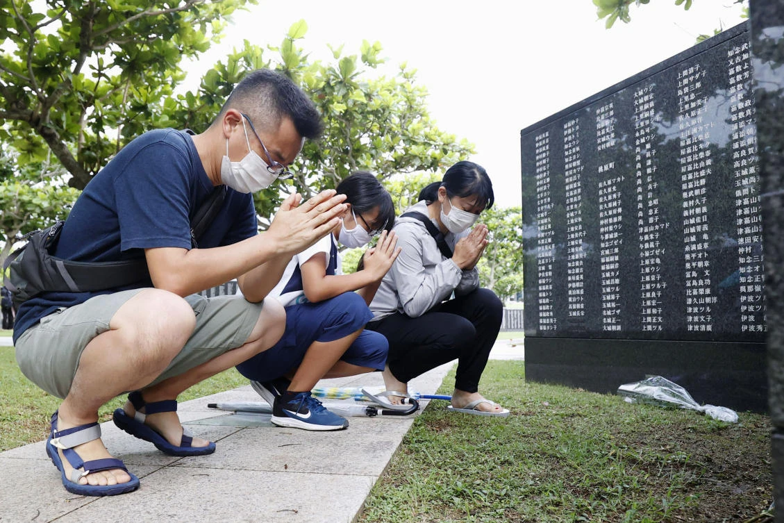 Members of a bereaved family pray in front of a "Cornerstone of Peace" monument wall on which the names of all those who lost their lives, both civilians and military of all nationalities in the Battle of Okinawa are engraved, at the Peace Memorial Park in Itoman, Okinawa, Japan, Tuesday, June 23, 2020. (AP)