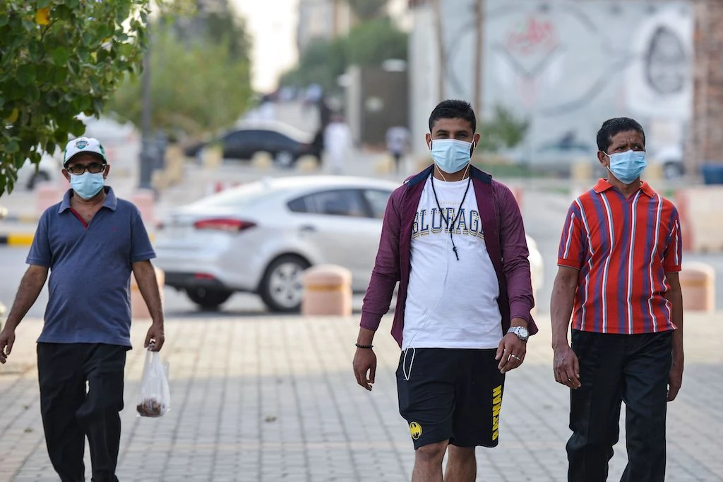 Mask-clad men walk along the promenade of Tahlia street in the centre of Saudi Arabia's capital Riyadh on June 21, 2020, as the country begins to re-open following the lifting of a lockdown due to the COVID-19 coronavirus pandemic. (AFP)