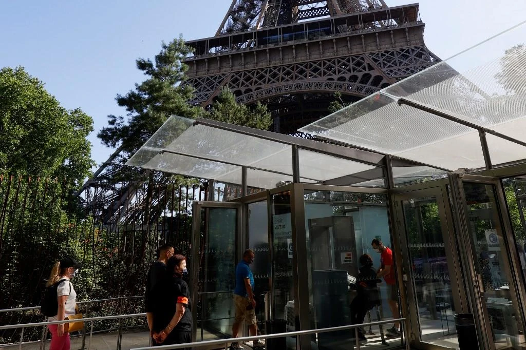 Visitors wearing protective facemasks queue as they wait for the partial reopening of Eiffel Tower. (AFP)