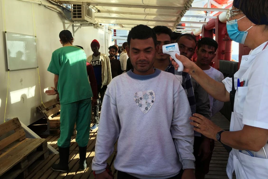 A medic of the French NGO SOS Mediterranee takes the temperature of migrants rescued by Ocean Viking crew members, off the coast of Lampedusa island, Italy, on June 25, 2020. (AFP)