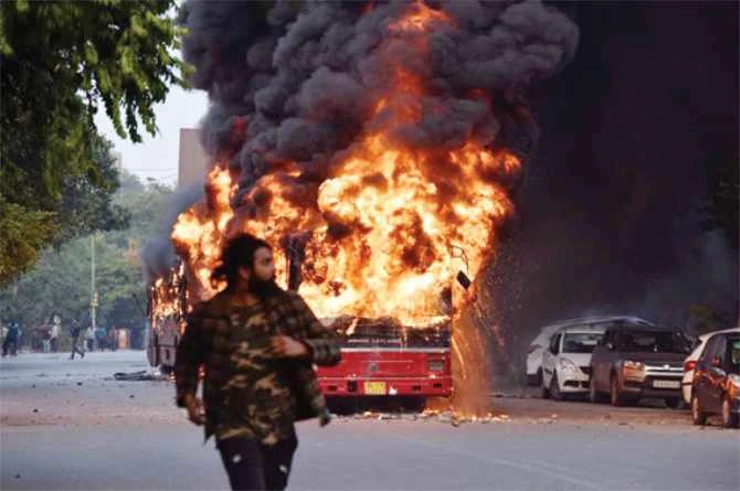 A man walks on a street as a bus is on fire following demonstration against the Indian government’s Citizenship Amendment Act (CAA) in New Delhi. (AFP file photo)