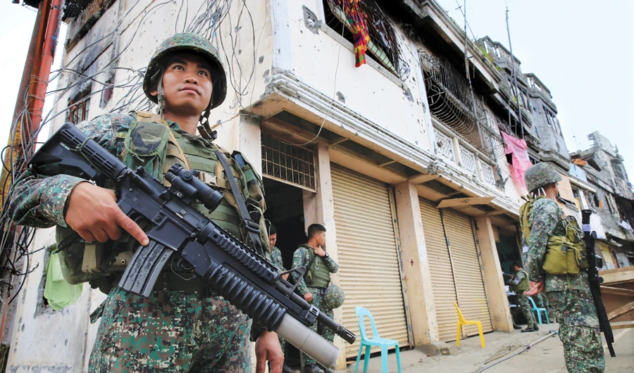 Filipino soldiers stand guard in front of damaged building and houses on Sultan Omar Dianalan Boulevard in the Mapandi district of Marawi city, Philippines. (File/Photo)