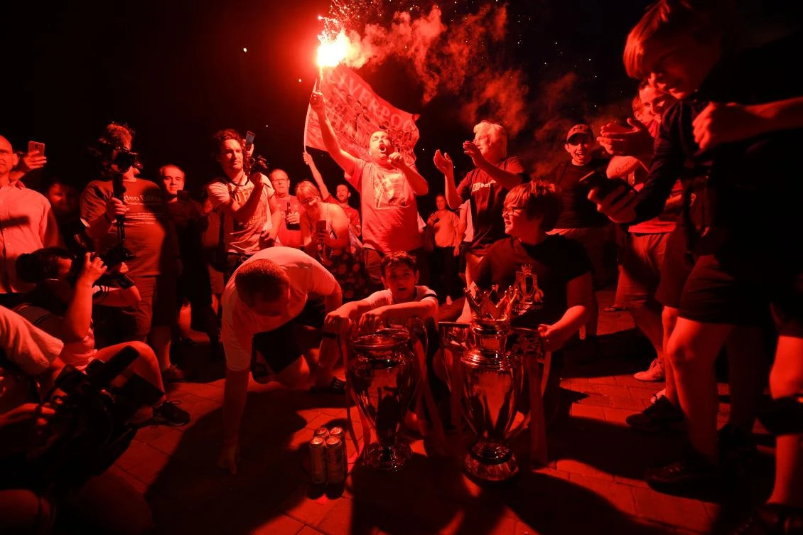 Fans celebrate Liverpool winning the championship title of the English Premier League following Chelsea's 2-1 victory over Manchester City, outside Anfield stadium in Liverpool, north west England on June 25, 2020. (AFP/Oli Scarff)