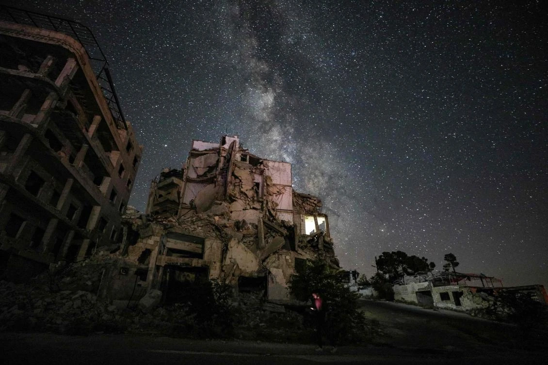 This long-exposure picture taken early on June 27, 2020 shows a man using an cell phone while walking past buildings destroyed by prior bombardment in the town of Ariha in Syria’s rebel-held northwestern Idlib province, as the Milky Way galaxy is seen in the night sky above. (AFP/Omar Hajj Kadour)
