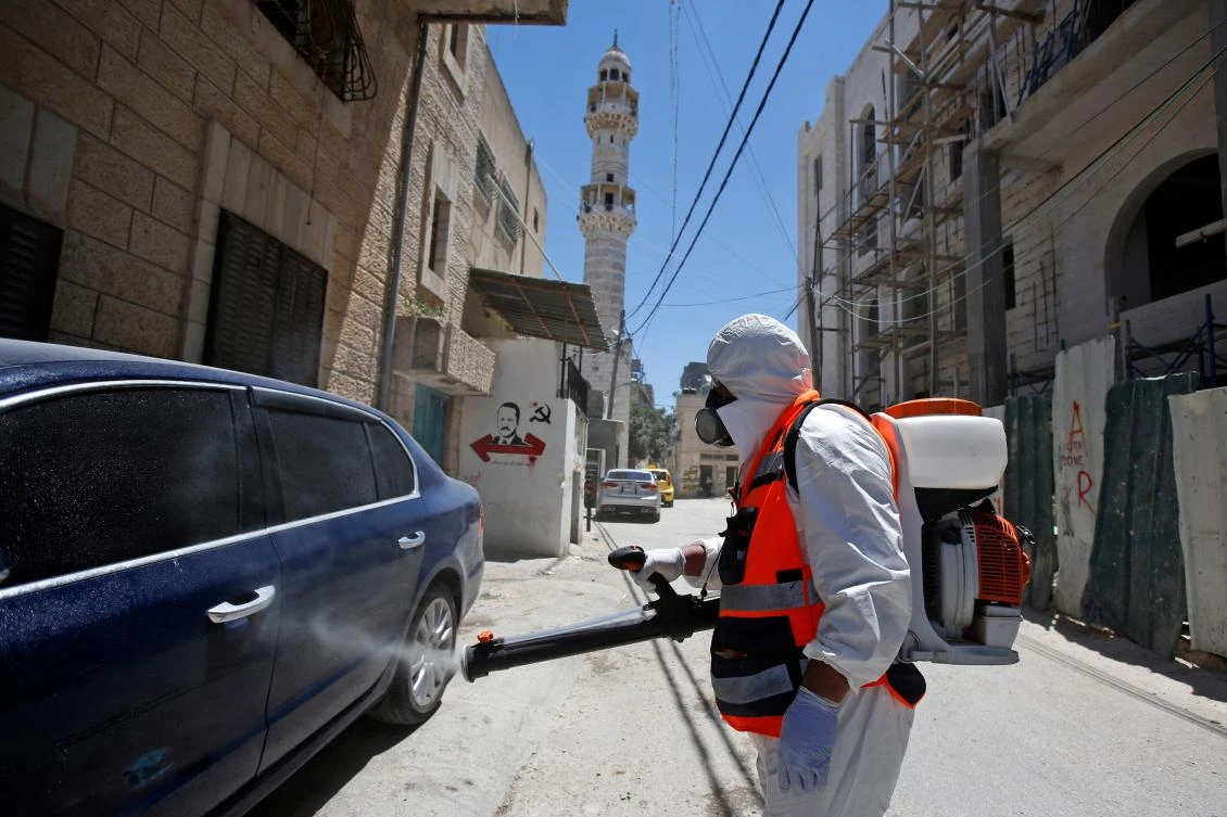 A worker of the Palestinian Bethlehem municipality in cooperation with the popular committee of Aida Refugee Camp, dressed in PPE (personal protective equipment), sterilises a street against Covid-19 coronavirus on June 25, 2020 in the Aida Refugee Camp near in the West Bank city of Bethlehem. (AFP)