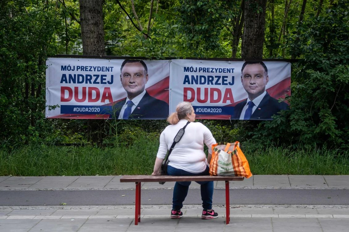 A woman sits in front of election posters of Polish President and candidate for Poland's president of main ruling party Law and Justice (PiS) in Warsaw, on June 25, 2020, a few days ahead of the presidential elections in Poland. The election was originally scheduled for May but had to be postponed due to the pandemic crisis. The first round is now scheduled for June 28. (AFP)