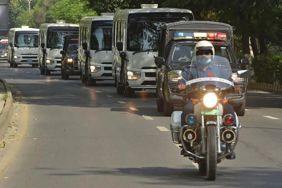 Police vans escort vehicles carrying Pakistan’s cricket team players as they leave for the airport in Lahore on June 28, 2020. (AFP)