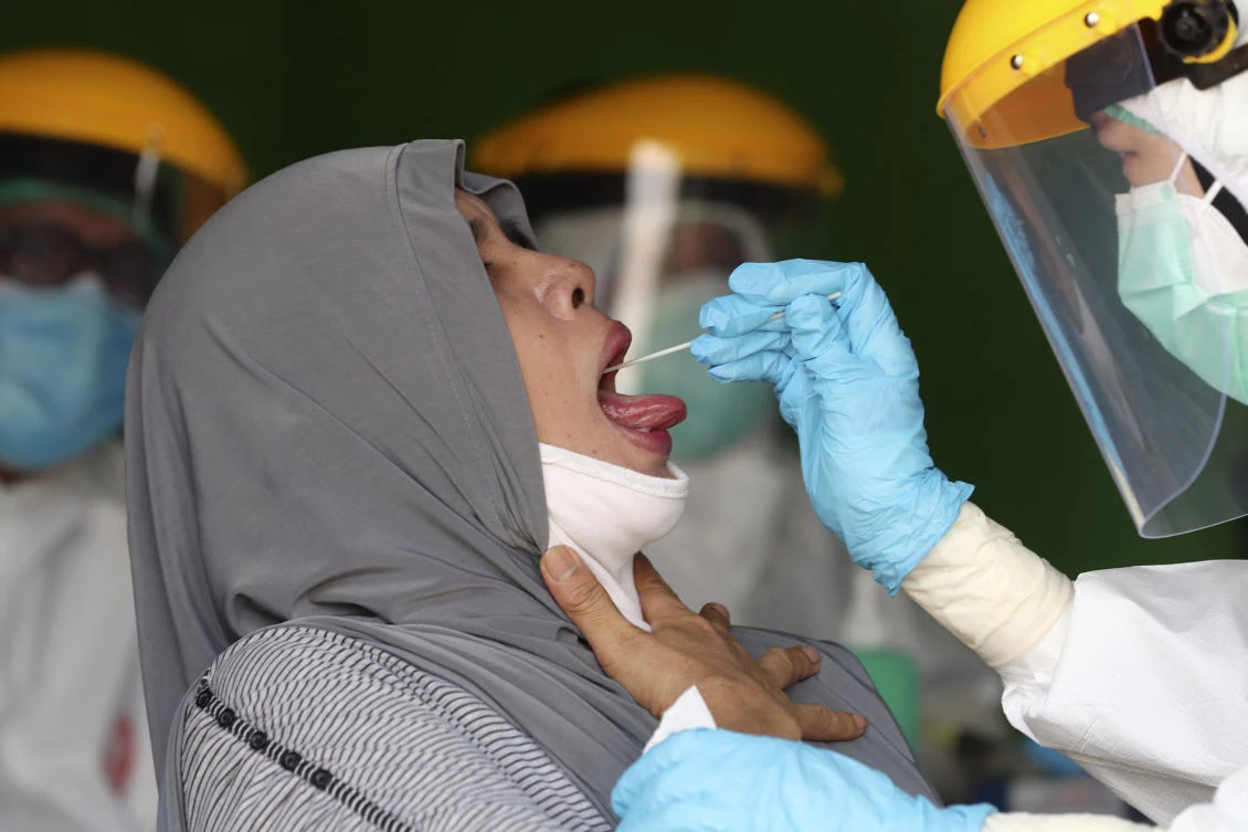 Health workers collect nasal swab samples from a woman during a mass test for the new coronavirus at a market in Jakarta, Indonesia, Thursday, June 25, 2020. (AP)