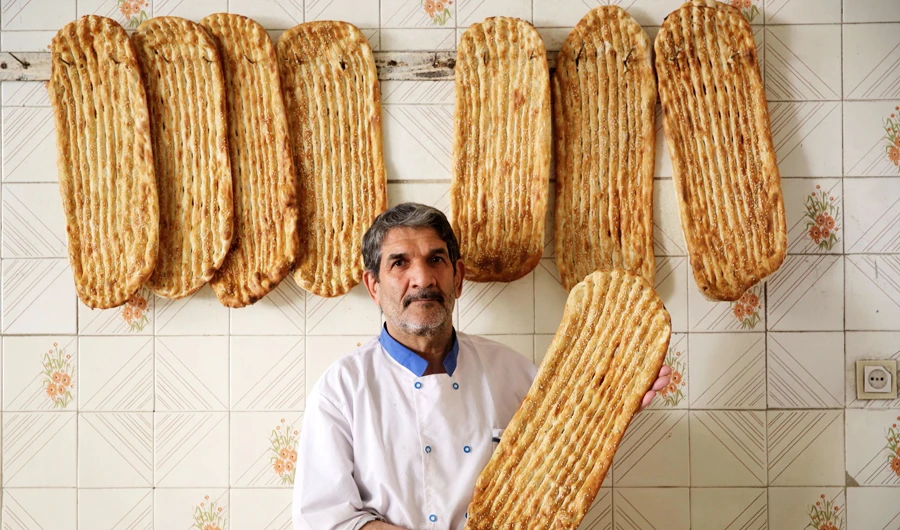 Iranian baker Esmail Asghari, 66, poses with Barbari bread in Tehran. (AFP)