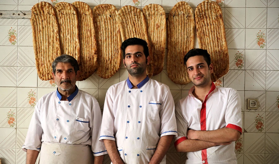 (L to R) Iranian bakers Esmail Asghari, 66, Farzad Rabiei, 30, and Mojtaba Haydari, 23, pose with Barbari bread in Tehran on June 7, 2020. (AFP)