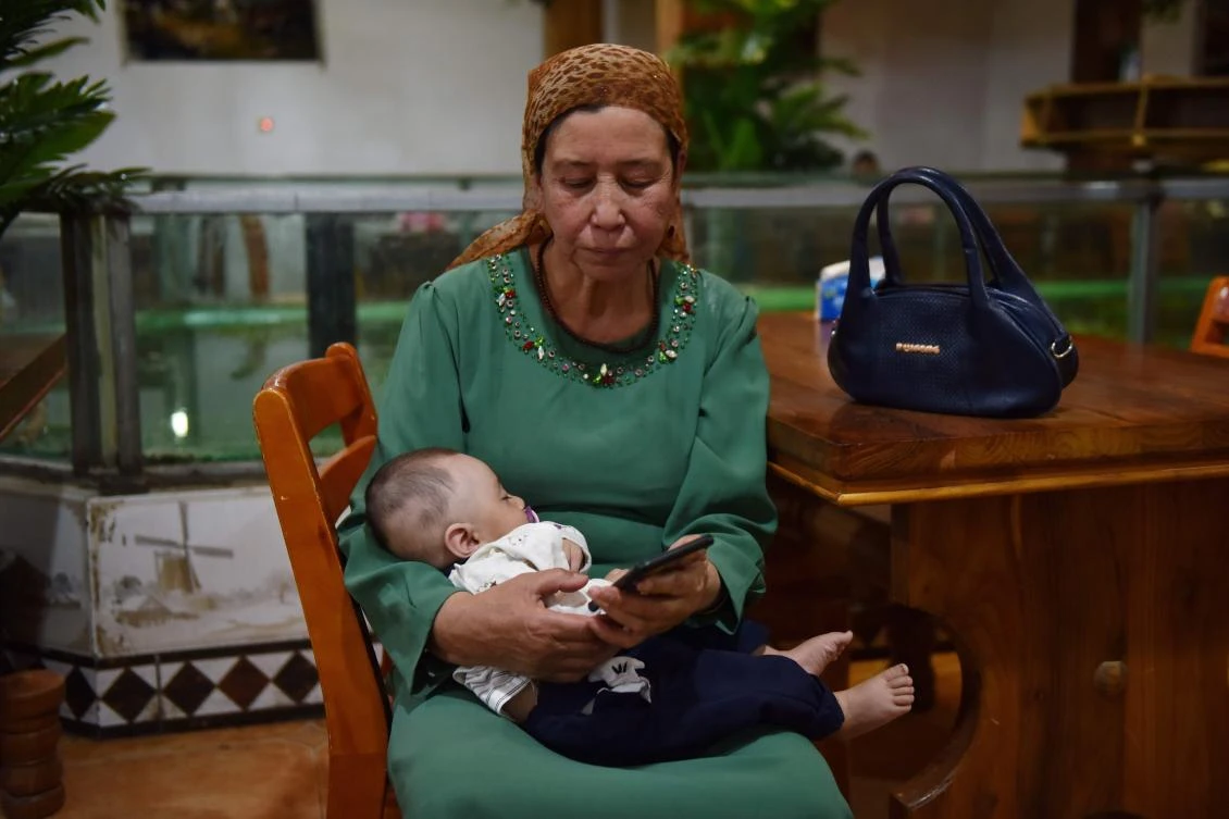 This file photo taken on May 31, 2019 shows a Uighur woman holding a baby in a Uighur restaurant in Hotan in China's northwest Xinjiang region. (AFP)