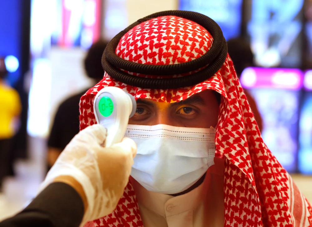 A Saudi cinema viewer has his temperature taken as he wears a face mask to help curb the spread of the coronavirus, at VOX Cinema hall in Jeddah. (AP)
