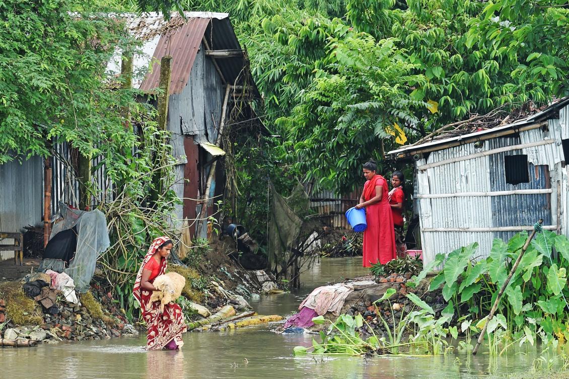 A woman carries her sheep as she walks through flood waters in Sunamgong on July 15, 2020. Almost four million people have been hit by monsoon floods in South Asia, officials said on July 14, with a third of Bangladesh already underwater from some of the heaviest rains in a decade. / AFP / Munir Uz zaman