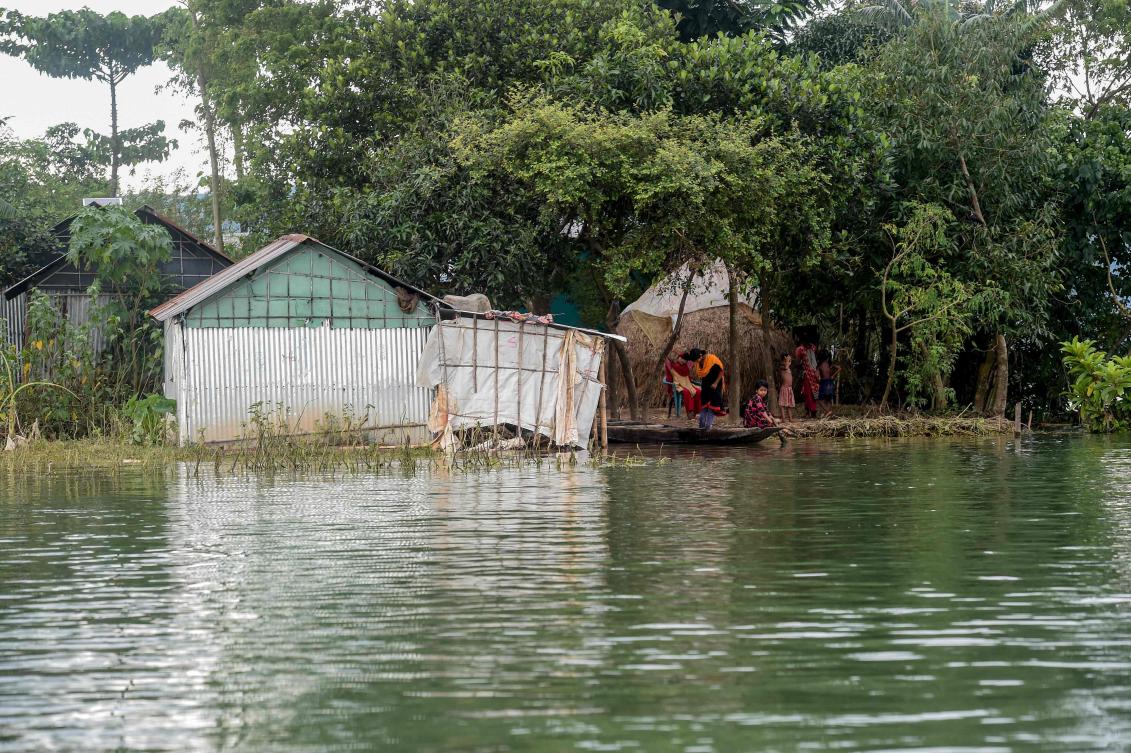 Children sit on a boat next a flooded house in Sunamganj on July 15, 2020. Almost four million people have been hit by monsoon floods in South Asia, officials said July 14, with a third of Bangladesh already underwater from some of the heaviest rains in a decade. / AFP / Munir Uz zaman