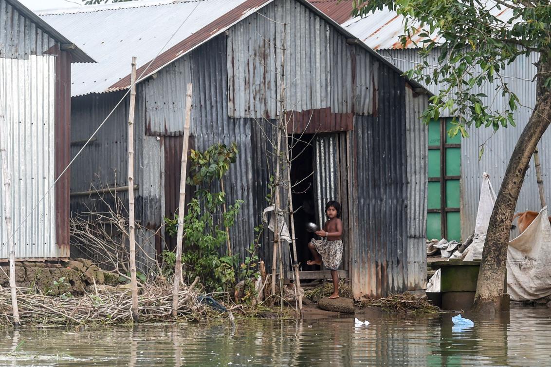 A child stands in front of a flooded house in Sunamganj on July 15, 2020. Almost four million people have been hit by monsoon floods in South Asia, officials said July 14, with a third of Bangladesh already underwater from some of the heaviest rains in a decade. / AFP / Munir Uz zaman