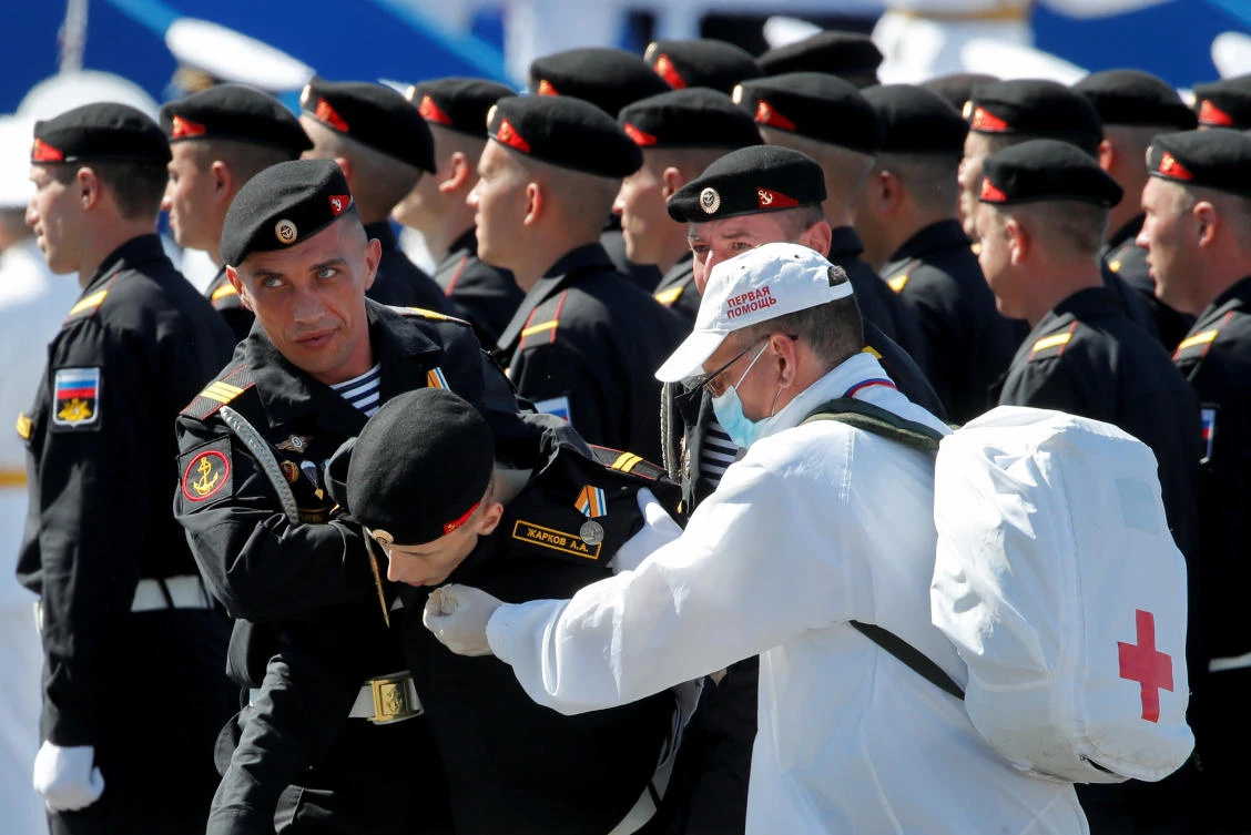 A Russian marine and a medical worker help a comrade not to fall prior the Navy Day parade in Saint Petersburg, Russia July 26, 2020. Dmitri Lovetsky/Pool via REUTERS