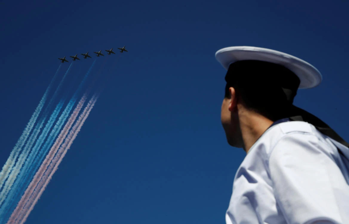 A Russian sailor watch as Su-25 jet fighters release smoke in the colours of the Russian state flag during the Navy Day parade in Kronstadt near Saint Petersburg, Russia July 26, 2020. REUTERS/Anton Vaganov/Pool