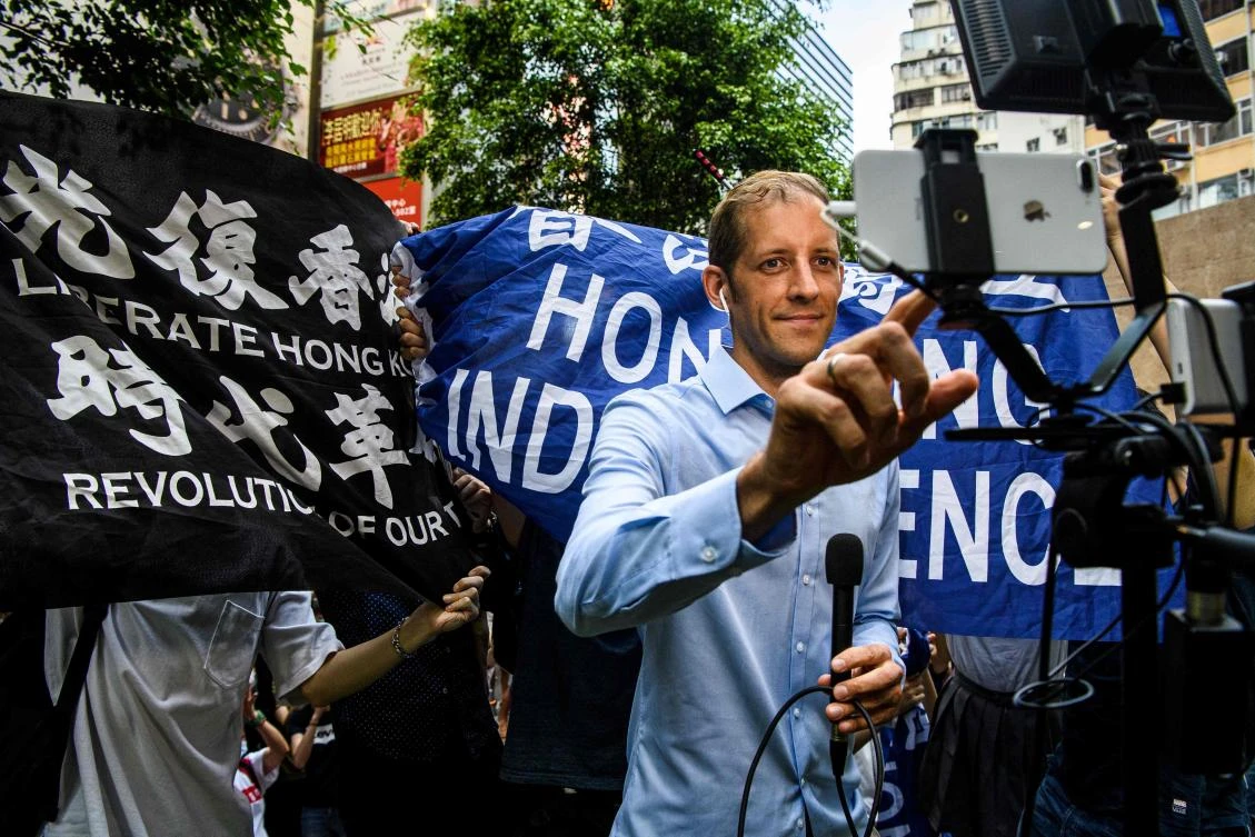 Protesters stand behind a reporter during a rally against a new national security law in Hong Kong on July 1, 2020, on the 23rd anniversary of the city’s handover from Britain to China. (AFP)