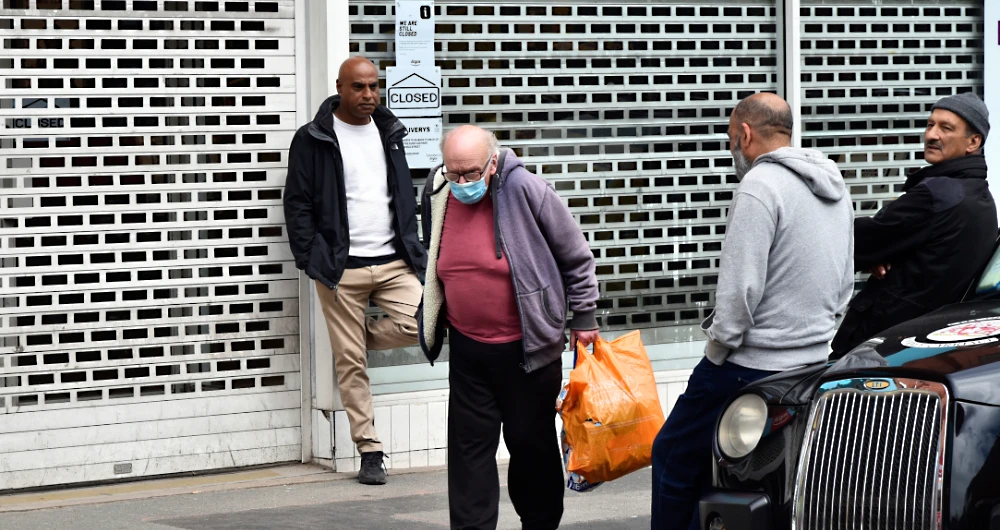 People stand outside a closed shop in Leicester city centre, England. (AP)