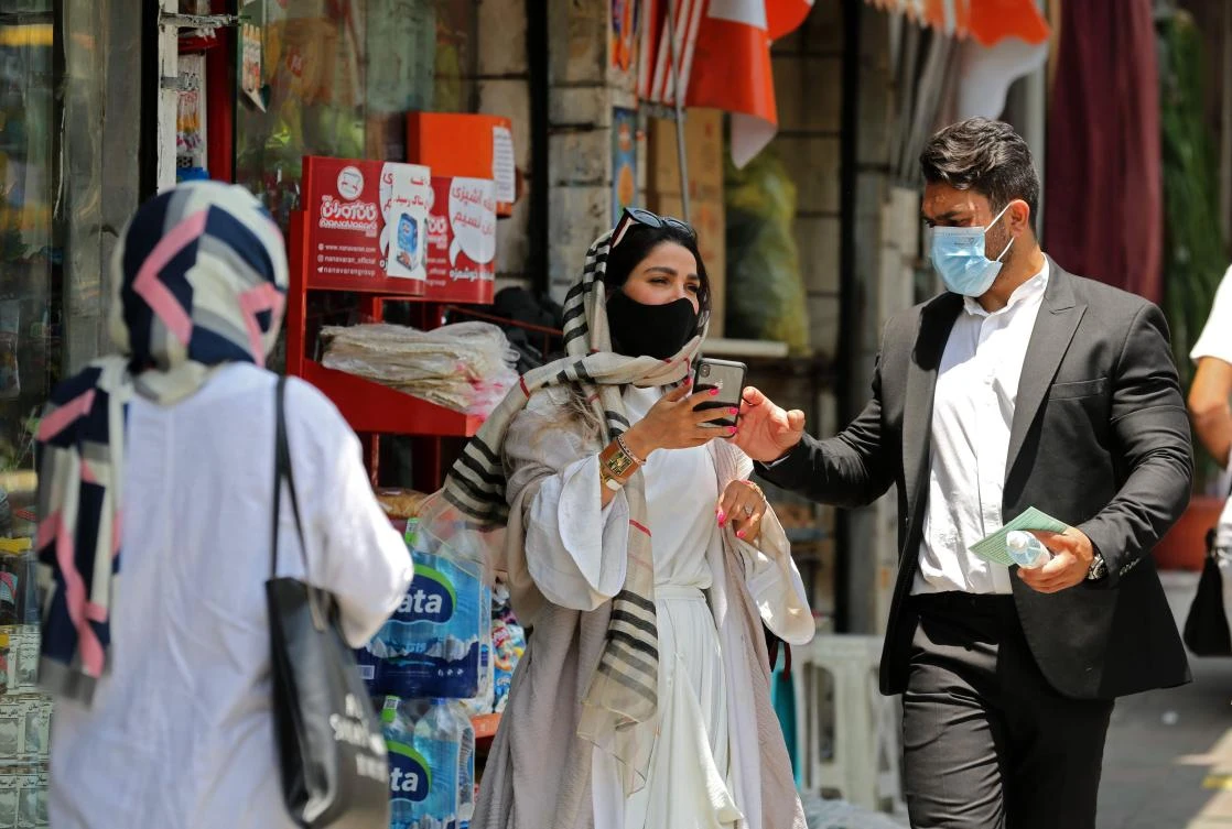Iranian pedestrians wearing protective masks due to the COVID-19 pandemic, walk along a street in the capital Tehran on July 1, 2020. (AFP)