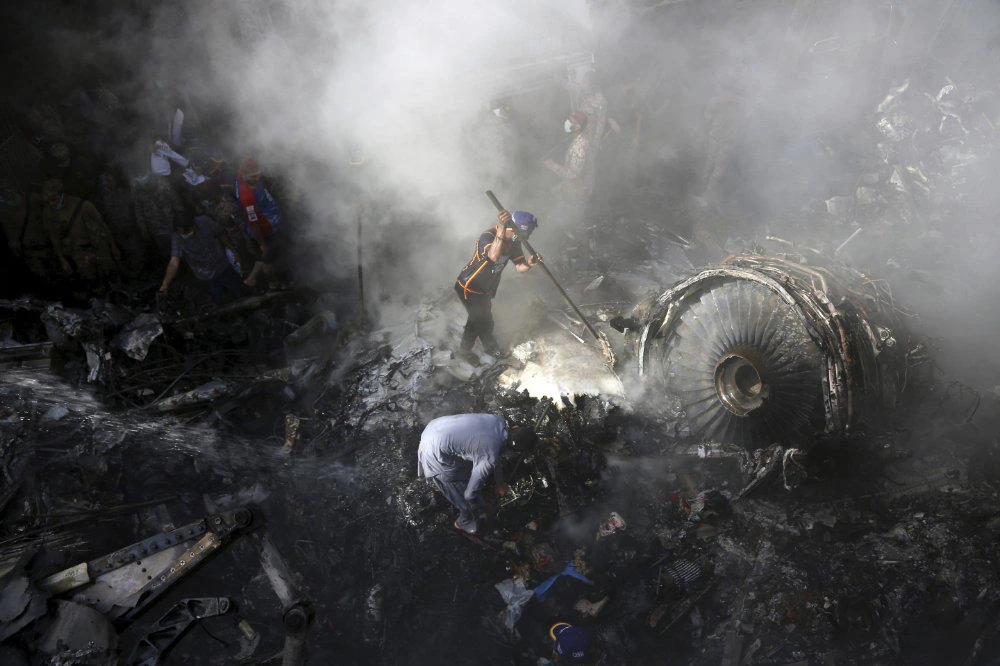 In this May 22, 2020 file photo, volunteers look for survivors of a Pakistan International Airlines plane that crashed in a residential area of Karachi, Pakistan. Pakistan last week grounded almost a third of its pilots after discovering they may have falsified their qualifications. (AP Photo/Fareed Khan, File)