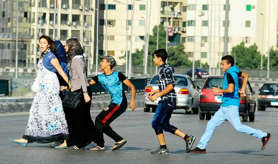 In this Aug. 20, 2012 file photo, an Egyptian youth, trailed by his friends, gropes a woman crossing the street with her friends in Cairo, Egypt. (AP)