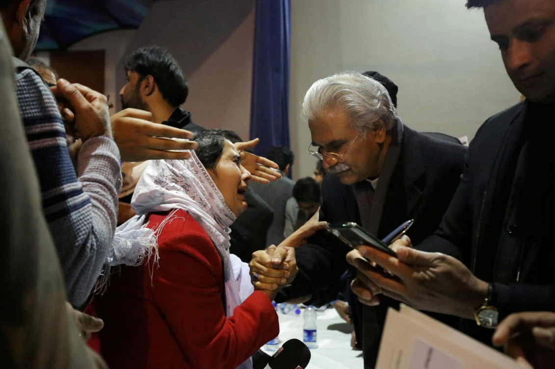 Pakistan's Health Minister, Zafar Mirza (R), interacts with the mother of a Pakistani student, who is stuck in the locked down Hubei province at the center of China's coronavirus outbreak, as people demand evacuation of their children during a meeting in Islamabad, Pakistan February 19, 2020. (Reuters)
